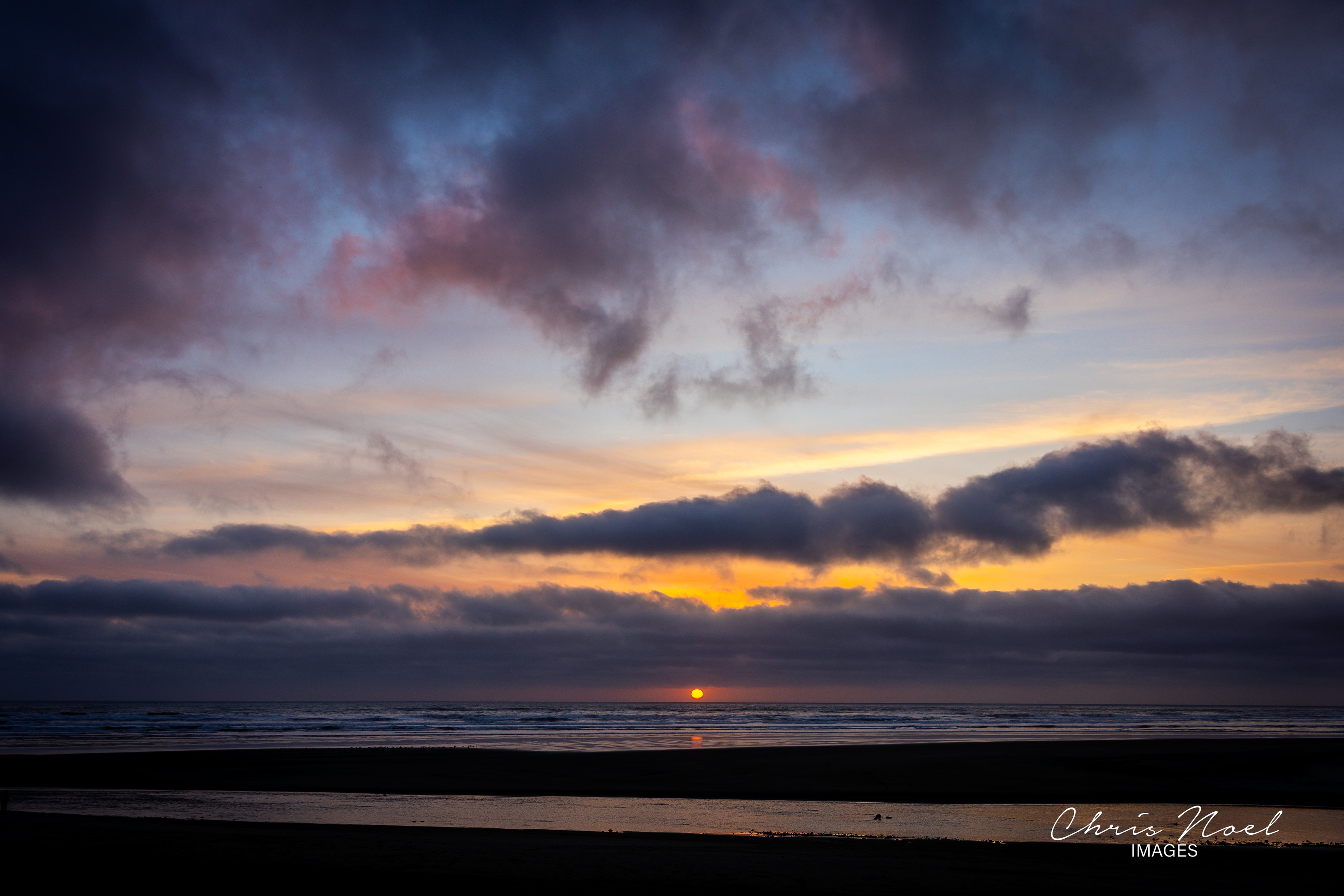 Dramatic Oregon beach sunset with vivid orange and purple clouds over the ocean